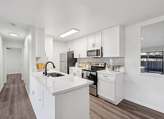 A modern kitchen with white cabinets and appliances.