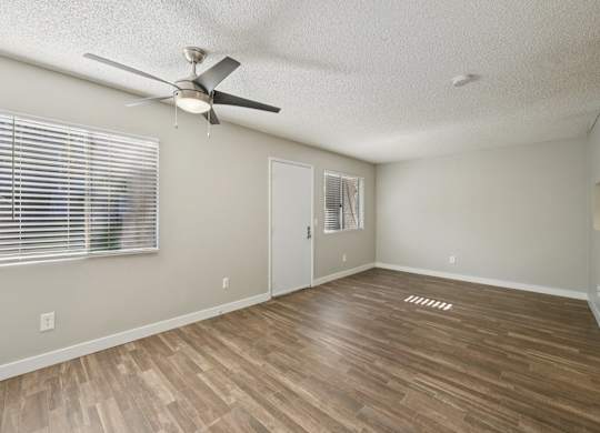 Model livingroom with a ceiling fan and wooden flooring.