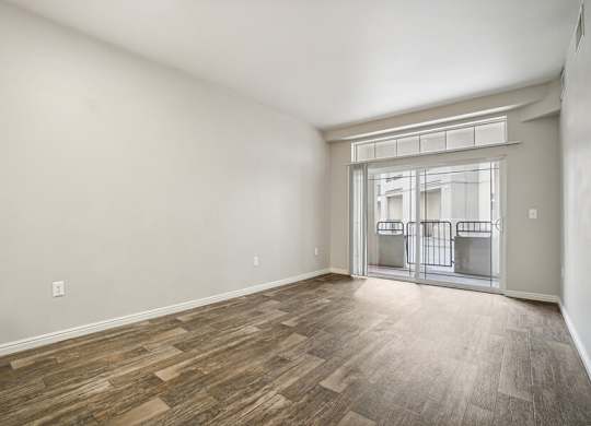 Model Living Room with Wood-Style Flooring and Patio Accessibility at Altitude on Fifth Apartments located in Salt Lake City, UT.