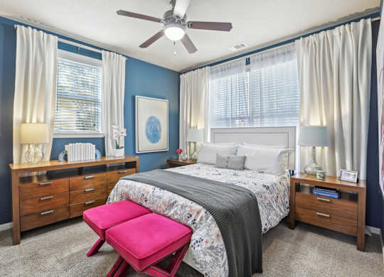 Model bedroom with queen bed and blue accent wall.
