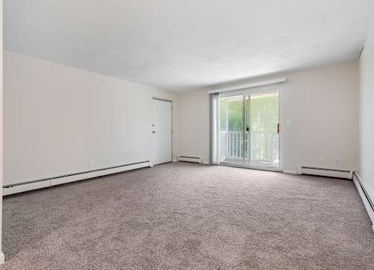 A large empty room with a carpeted floor and a sliding glass door.
