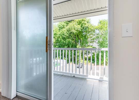 A glass door opens to a balcony with a white railing.