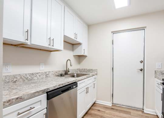 A kitchen with white cabinets and a marble countertop.