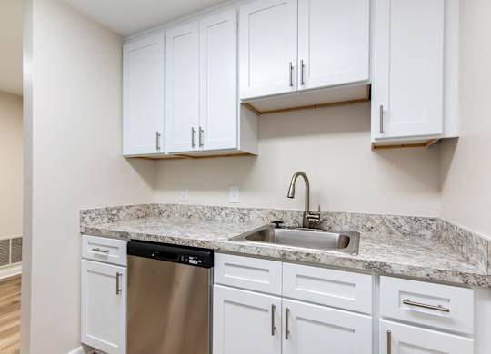 A kitchen with white cabinets and a granite countertop.