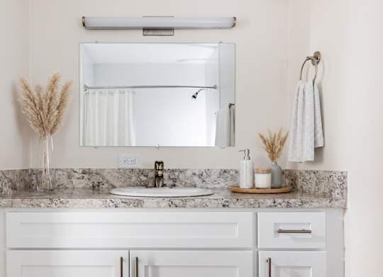 A bathroom with a marble countertop and white cabinets.