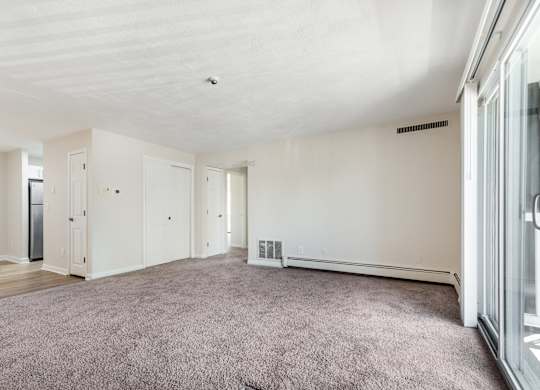 A spacious room with a grey carpet and white walls.