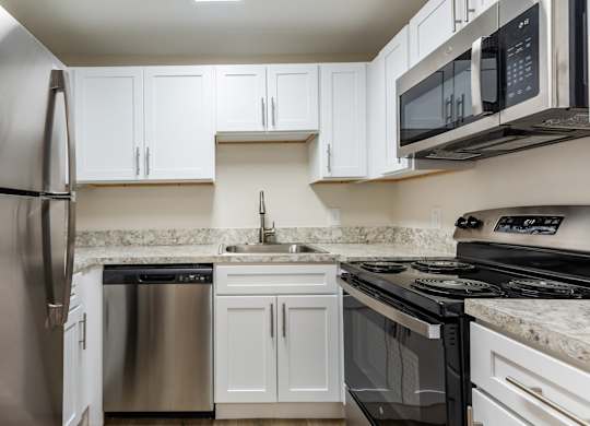 A modern kitchen with white cabinets and stainless steel appliances.