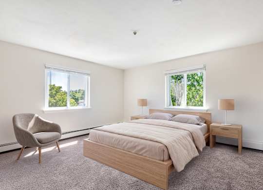 A bedroom with a bed, chair, and two windows.