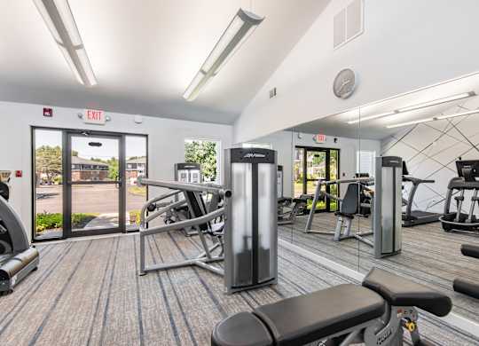 A gym with a variety of equipment including treadmills, weights, and exercise machines.