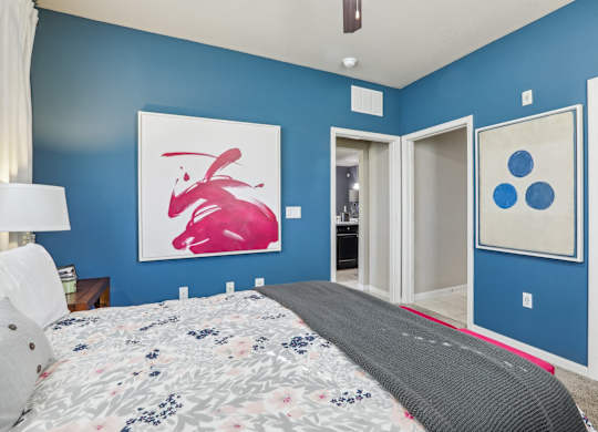 Model bedroom with a large bed and a painting on the wall.