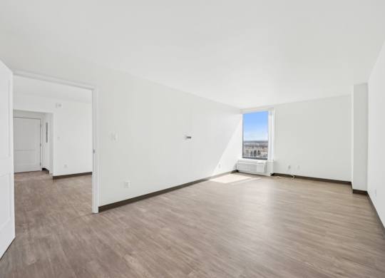 A large empty room with wooden floors and white walls.
