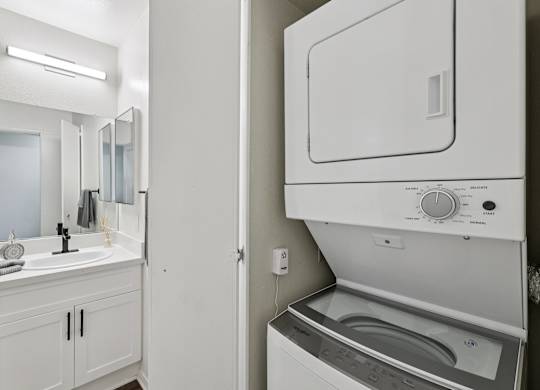 A white bathroom with a washer and dryer built into the wall.
