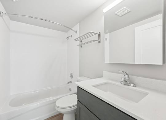 A white bathroom with a toilet, sink, and bathtub.