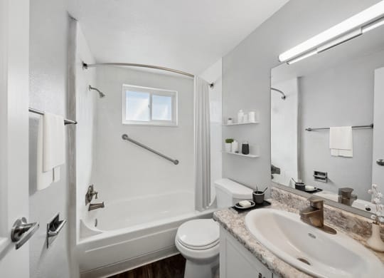 Model Bathroom with White Cabinets, Wood-Style Flooring and Shower/Tub at Esprit at Cherry Creek Apartments in Glendale, CO.