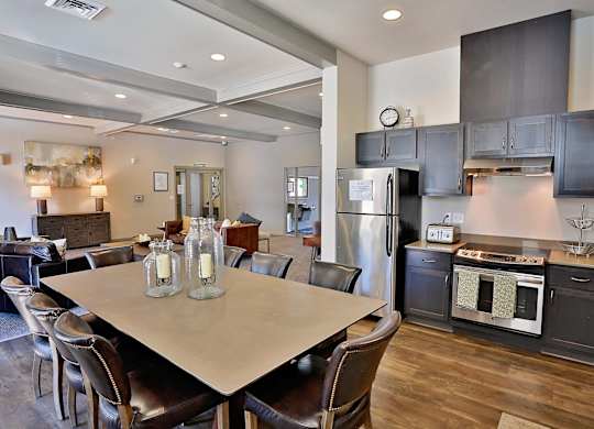 A modern kitchen with a communal dining table and chairs.