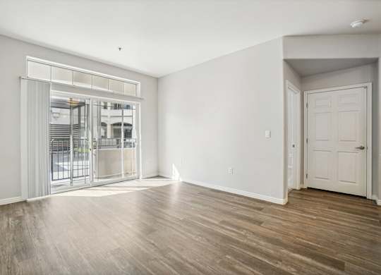 Model Living Room with Wood-Style Flooring and Patio Accessibility at Altitude on Fifth Apartments located in Salt Lake City, UT.