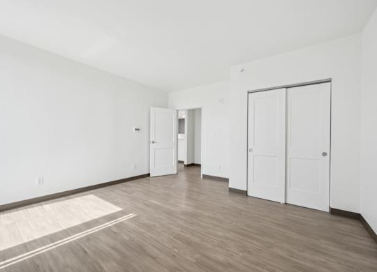 A room with white walls and wooden flooring with a rug on the floor.
