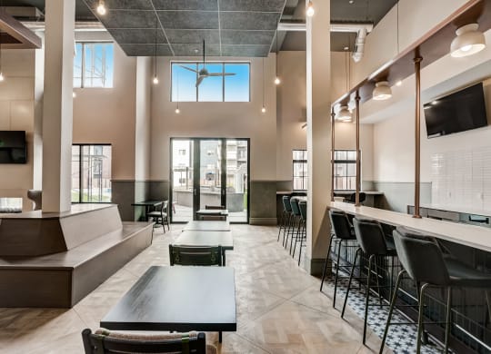 a large lobby with tables and chairs and a bar with chairs