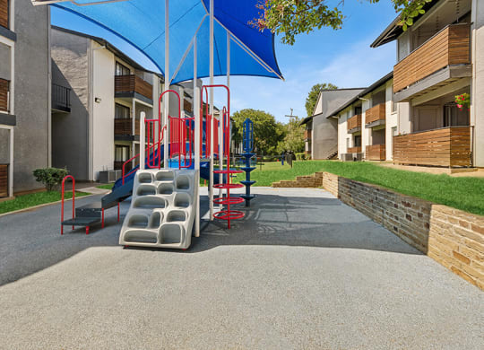 Community Playground with Slide and Blue Canopy at Summit Ridge Apartments located in Arlington, TX.