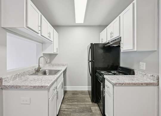 Model kitchen with a black refrigerator and white cabinets.