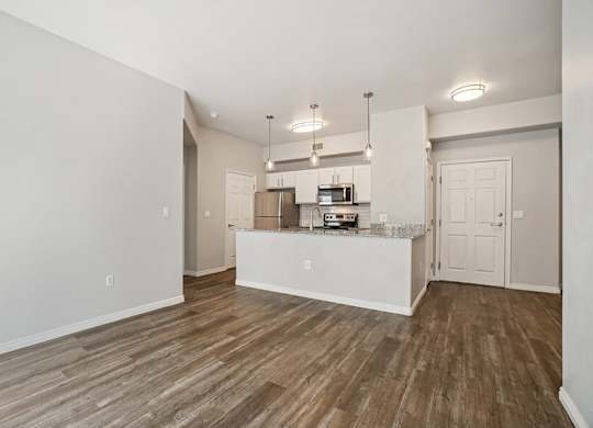 Model Living Room and Kitchen with Wood-Style Flooring at Altitude on Fifth Apartments located in Salt Lake City, UT.