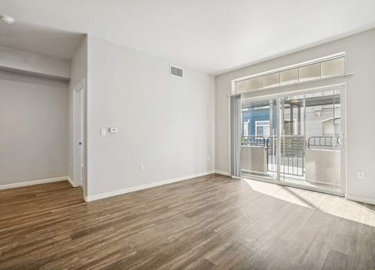 Model Living Room with Wood-Style Flooring and Patio Accessibility at Altitude on Fifth Apartments located in Salt Lake City, UT.
