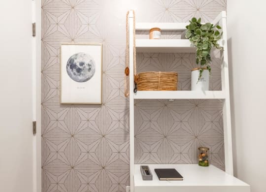 a small workspace with a white desk and a white shelf and a chair