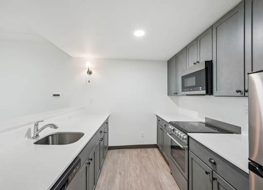 A modern kitchen with stainless steel appliances and wooden flooring.