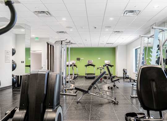 A gym with a variety of equipment including treadmills, weights, and exercise machines.