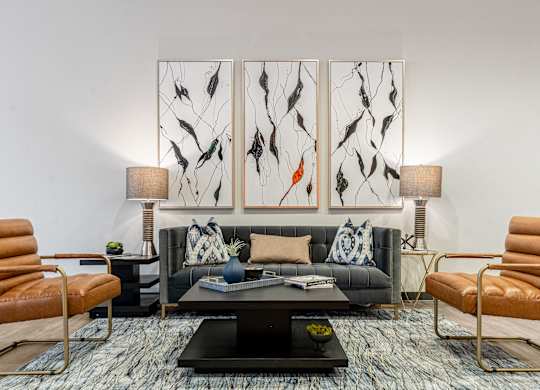 A living room with a black couch, a coffee table, and two chairs.