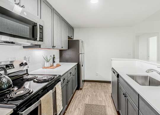 A kitchen with a black stove top oven and a black microwave above it.