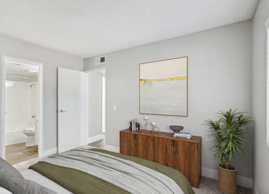 a bedroom with a bed and a potted plant    and a bathroom