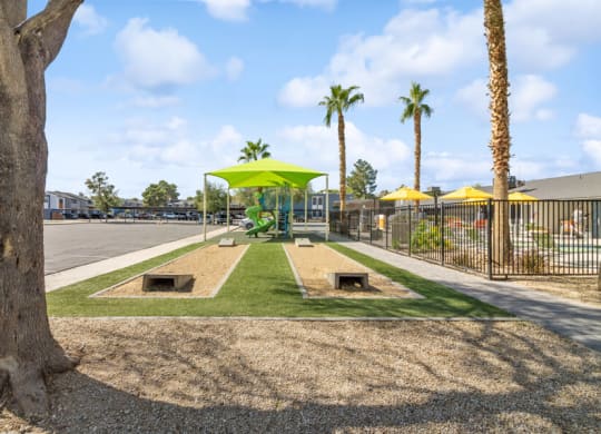 a park with palm trees and cornhole and a playground