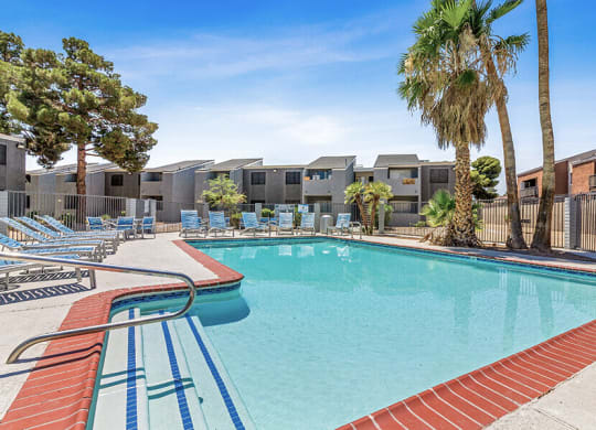 a swimming pool with chairs and palm trees