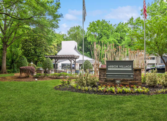 a view of the arbor village sign with a tent and trees in the background