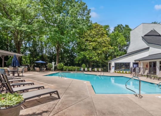 a swimming pool with chaise lounge chairs and a building in the background