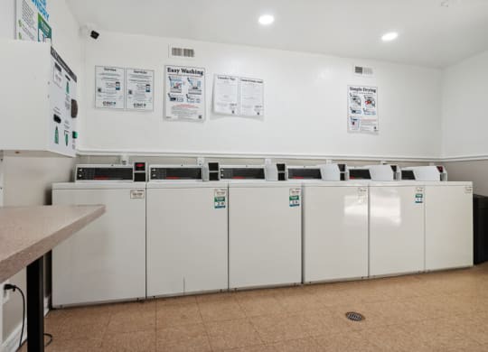 a laundry room with many washers and dryers
