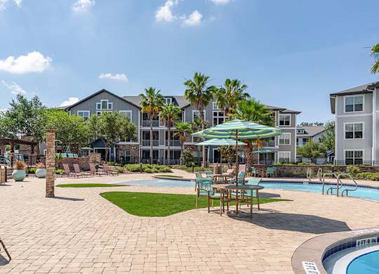 A pool area with a hot tub and chairs.