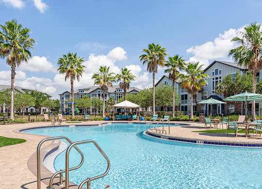 A swimming pool surrounded by palm trees and lounge chairs.