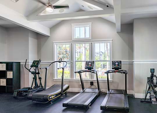 A gym with treadmills and a fan.