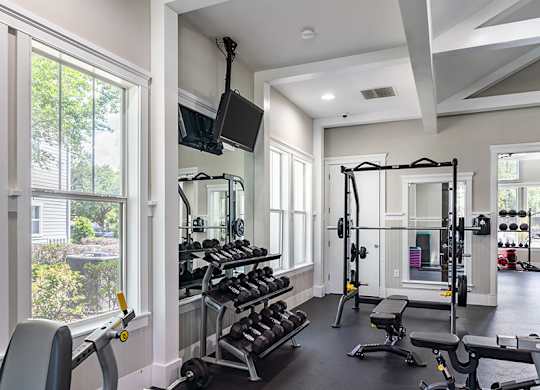 A well-lit home gym with a variety of exercise equipment.