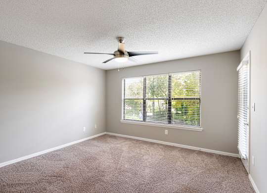 Model bedroom with windows, carpet, and ceiling fan at Fountains at Lee Vista in Orlando, Florida.