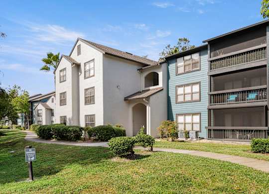 Community apartment building with grass and walking path at Fountains at Lee Vista in Orlando, Florida.