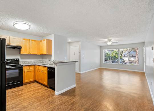 Model view of kitchen counter and living room with wood flooring at Huntington Place in Sarasota, Florida.