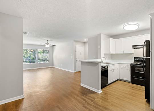 Model view of kitchen counter and living room  with wood flooring at Huntington Place in Sarasota, Florida.
