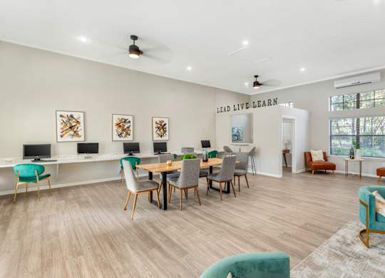 A room with a long table and chairs, a whiteboard, and a wall with a quote on it.