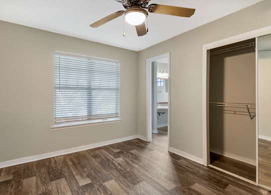 Model bedroom with sliding door closet, hard wood vinyl flooring, and ceiling fan at Mirage on Kernan in Jacksonville, Florida.