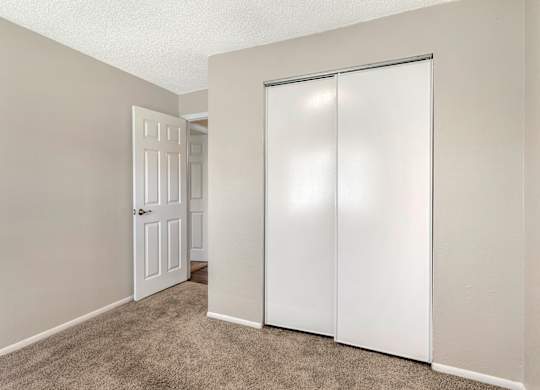 Model bedroom with sliding closet door and carpet flooring at Park at 7200 in Jacksonville, Florida.