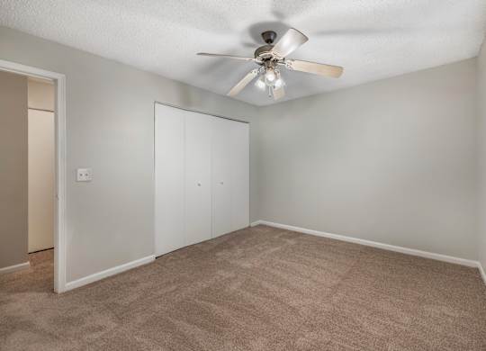 A room with a ceiling fan and carpeted floor.