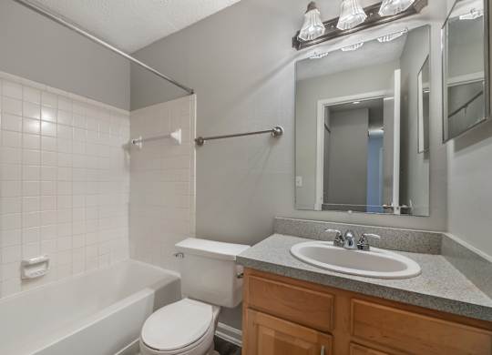A white tiled bathroom with a toilet, sink, and bathtub.